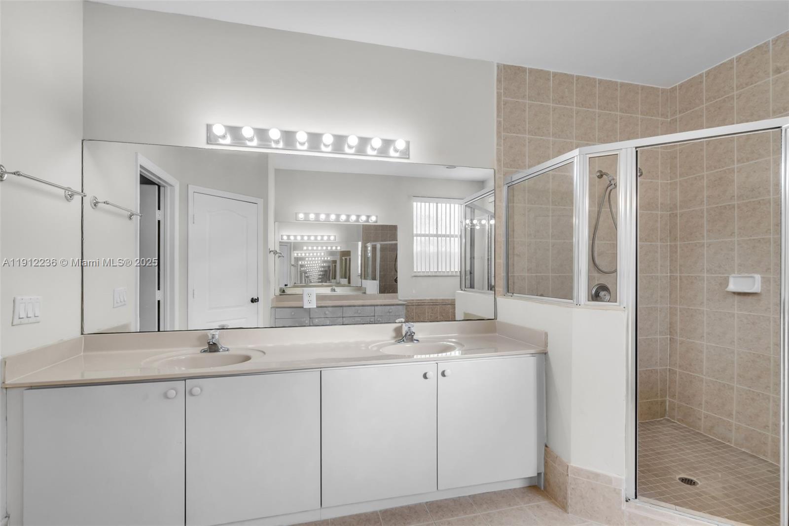 8920 Northwest 180th Terrace Hialeah, FL 33018 - Photo 26 of 44 a bathroom with a double vanity sink and a mirror