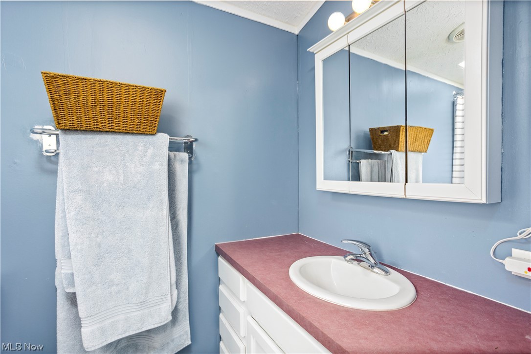 168 Coen Road Vermilion, OH 44089 - Photo 23 of 29 Bathroom with a textured ceiling, crown molding, mirror, and large vanity