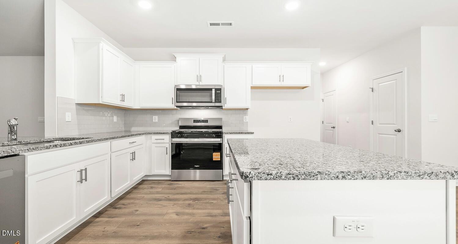 1383 Lansdowne Drive, Unit 401 Mebane, NC 27302 - Photo 13 of 23 a kitchen with stainless steel appliances granite countertop a sink stove and refrigerator