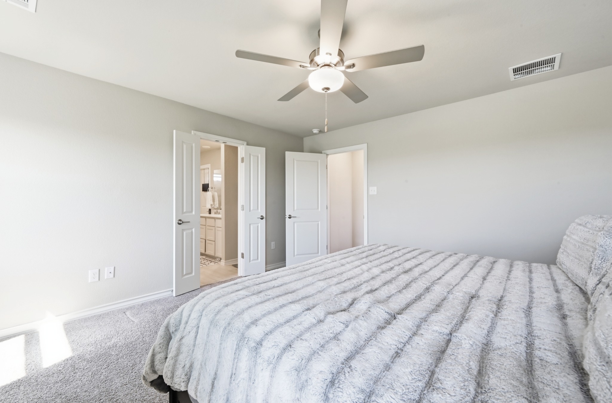 488 Pepperbark Loop Buda, TX 78610 - Photo 19 of 31 Plush carpeting and a classic ceiling fan enhance this inviting bedroom, offering a comfortable retreat.