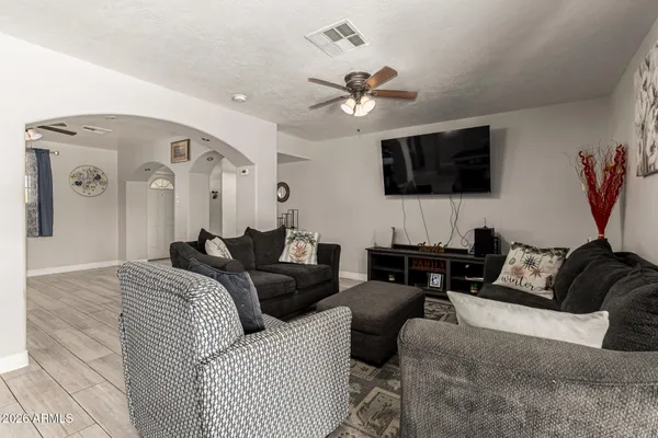 a living room with furniture a flat screen tv and a ceiling fan