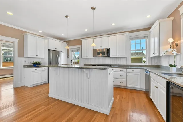 a kitchen with kitchen island granite countertop a sink cabinets and wooden floor