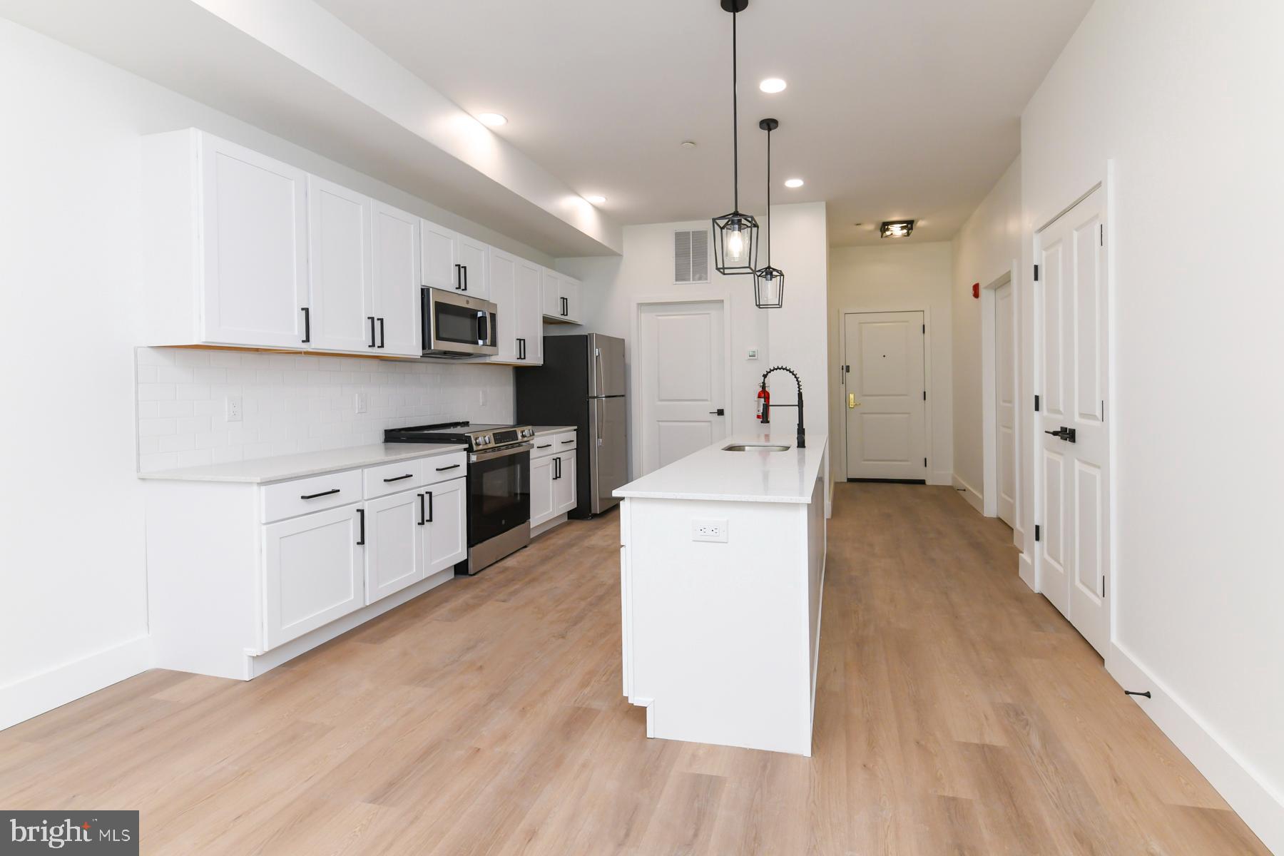 100 Aura Road, Unit 111 Clayton, NJ 08312 - Photo 23 of 34 a kitchen with kitchen island white cabinets and wooden floor