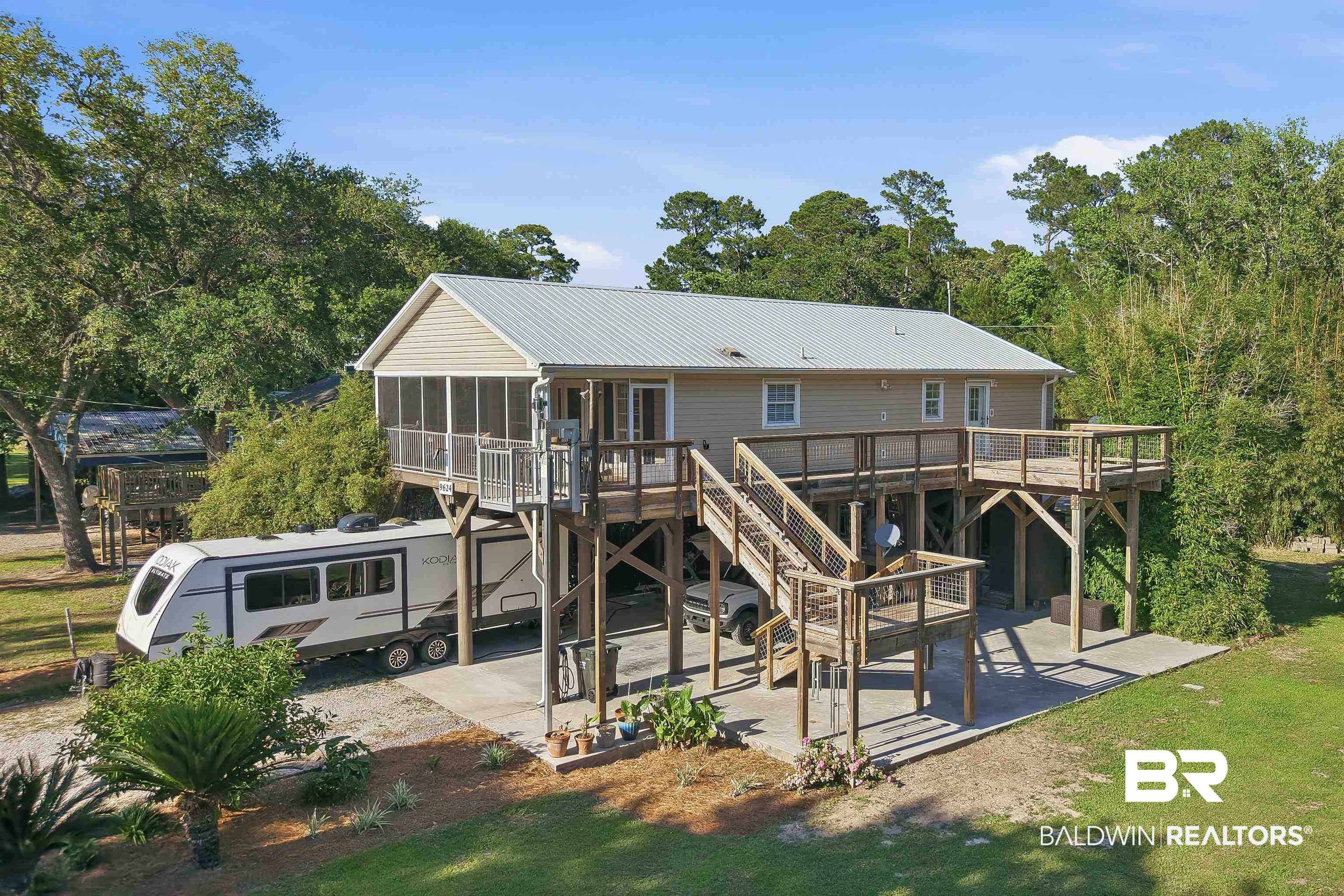 9624 North Bay Street Foley, AL 36535 - Photo 41 of 59 Elevated residence featuring a metal roof, screened porch, and extensive exterior decking