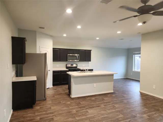 a view of kitchen with microwave stove refrigerator and cabinets