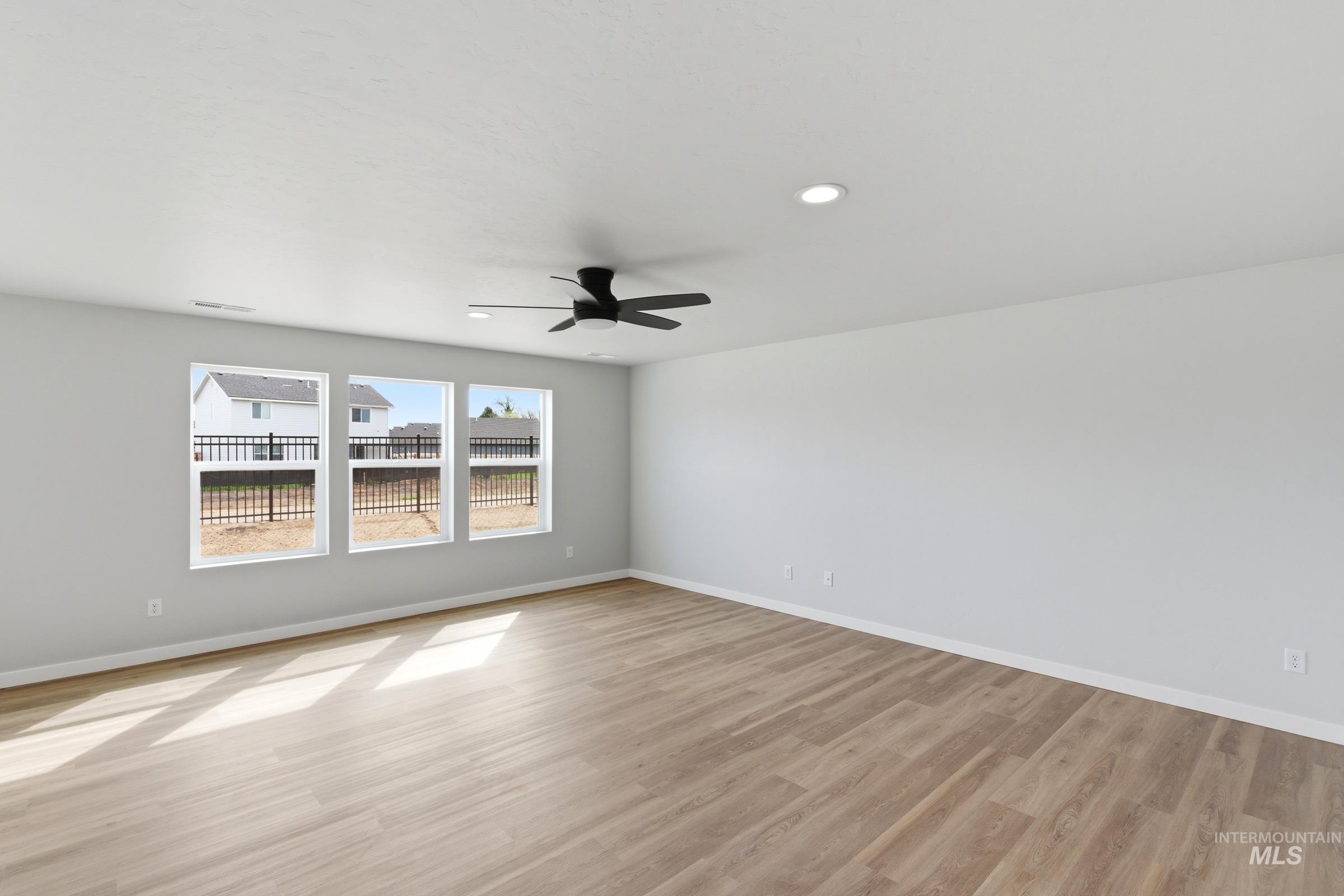 16558 Dunning Way Caldwell, ID 83607 - Photo 7 of 35 Spacious room featuring light wood-finish flooring, three large windows, a ceiling fan, recessed lighting, and crisp white walls with matching trim