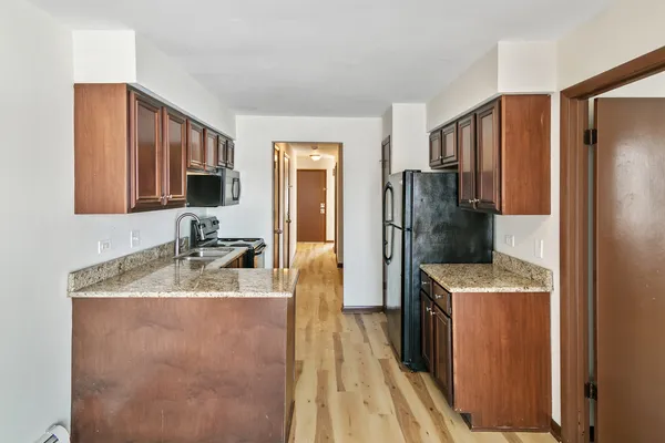 a kitchen with a refrigerator sink and wooden cabinets