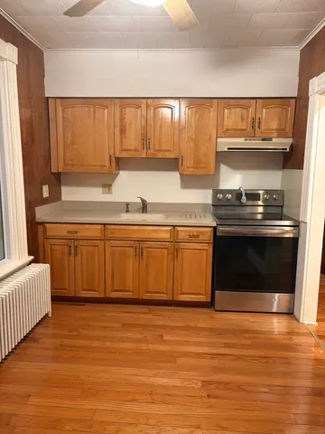 a kitchen with stainless steel appliances granite countertop a sink cabinets and wooden floor