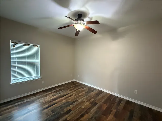 a view of a room with wooden floor ceiling fan and window