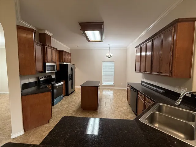 a kitchen with granite countertop stainless steel appliances a sink stove refrigerator and cabinets