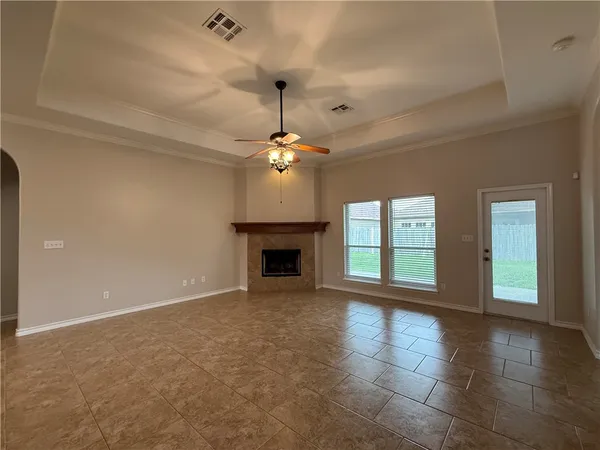 a view of an empty room with window and chandelier fan