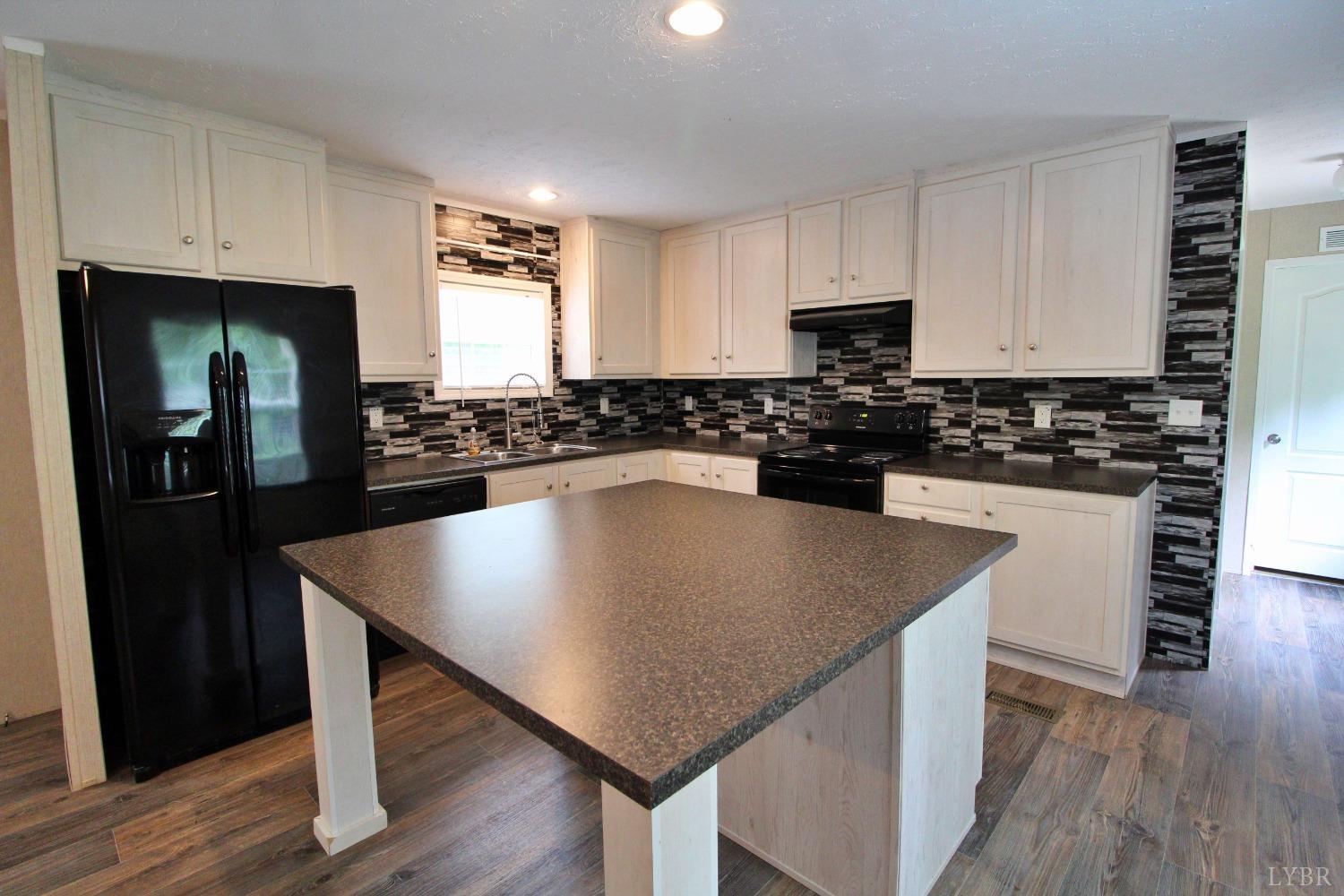 1104 Holiday Lake Road Pamplin, VA 23958 - Photo 3 of 19 a kitchen with stainless steel appliances granite countertop a stove a refrigerator a sink a stove and white cabinets with wooden floor