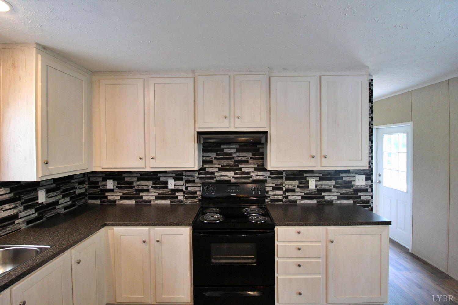 1104 Holiday Lake Road Pamplin, VA 23958 - Photo 5 of 19 a kitchen with granite countertop white cabinets and black appliances