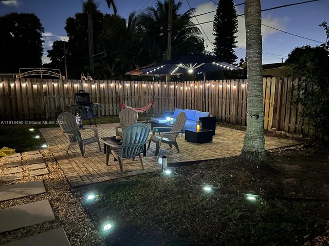 a view of a patio with table and chairs with plants and wooden fence