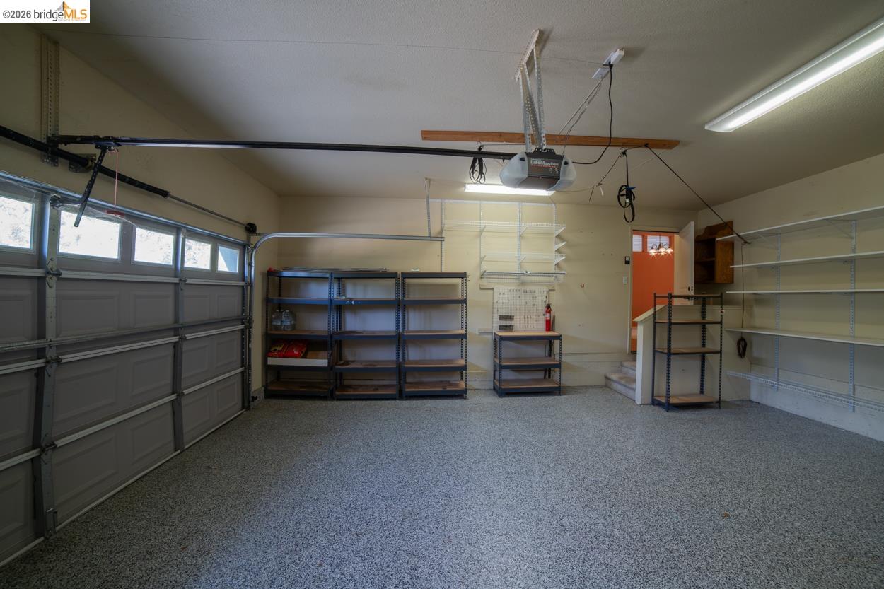 22401 Ridge Road Twain Harte, CA 95383 - Photo 30 of 52 Spacious garage featuring a durable epoxy floor coating, automated garage door, fluorescent lighting, and extensive built-in shelving