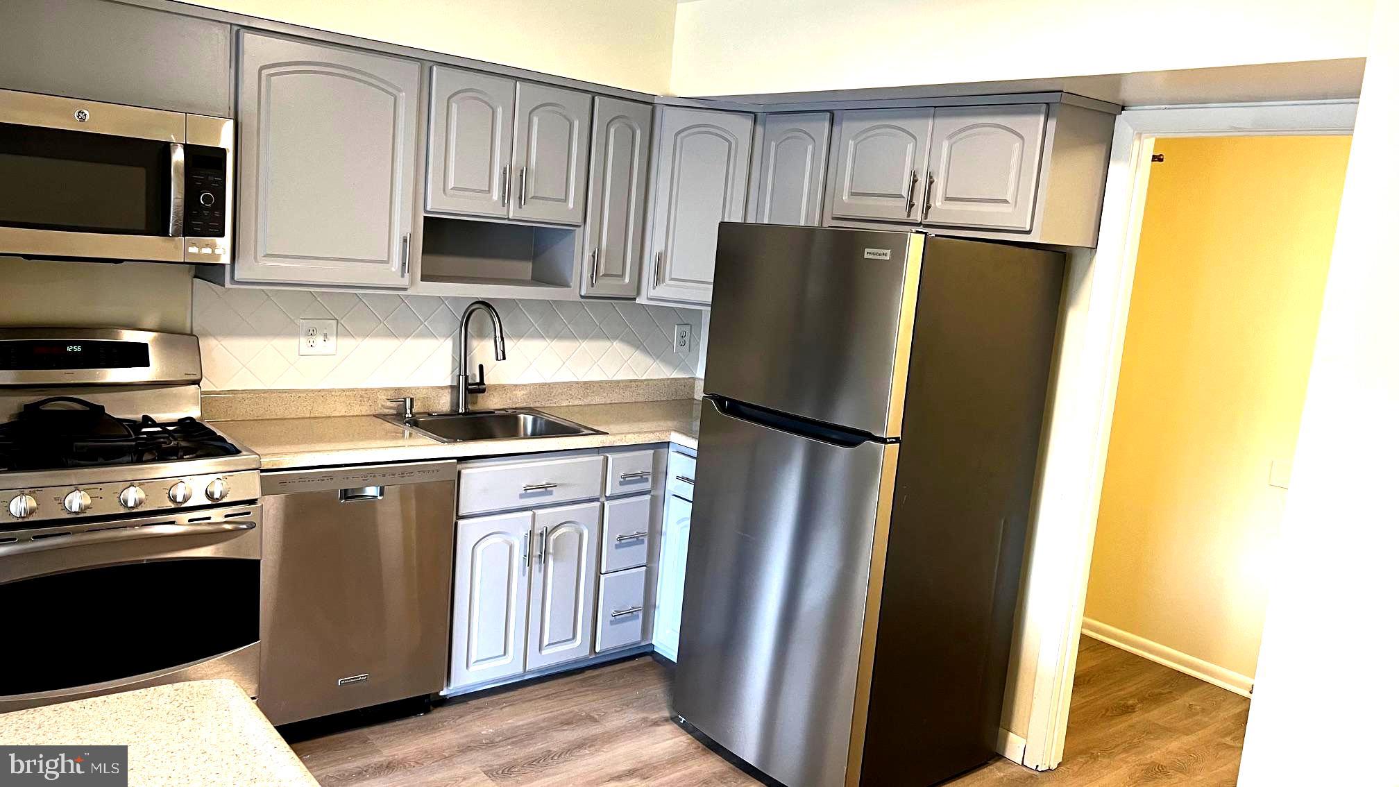 10073 Windstream Drive, Unit 5 Columbia, MD 21044 - Photo 4 of 17 a kitchen with stainless steel appliances granite countertop a refrigerator a stove a sink and a microwave