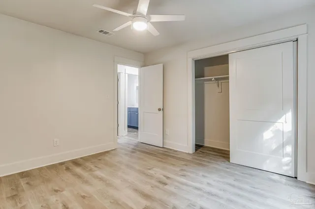 a view of empty room with wooden floor and fan