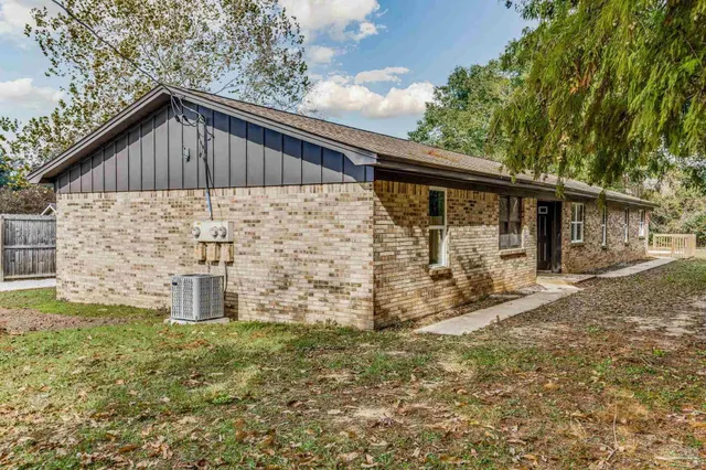 a backyard of a house with large trees and brick walls
