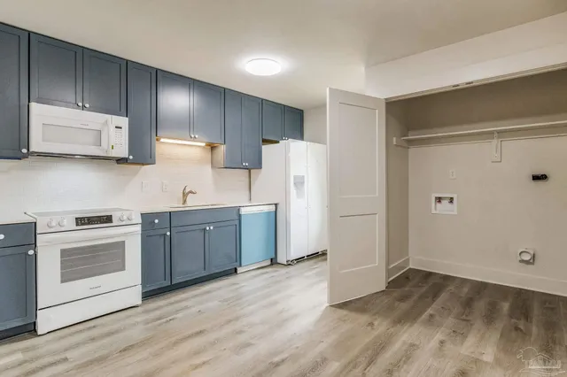 a kitchen with a sink cabinets stainless steel appliances and wooden floor