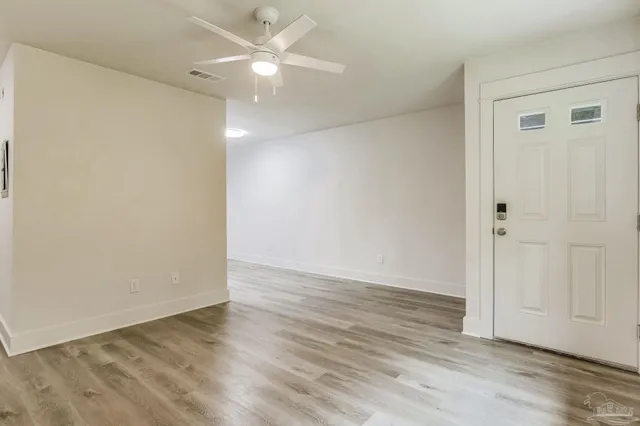 an empty room with wooden floor and fan