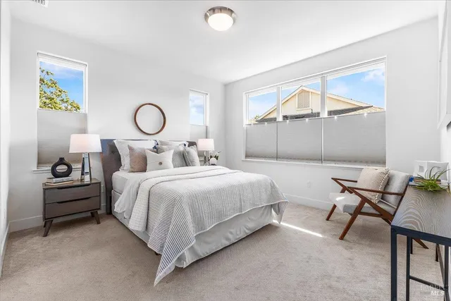 a bedroom with a bed a chair and painting on the wall