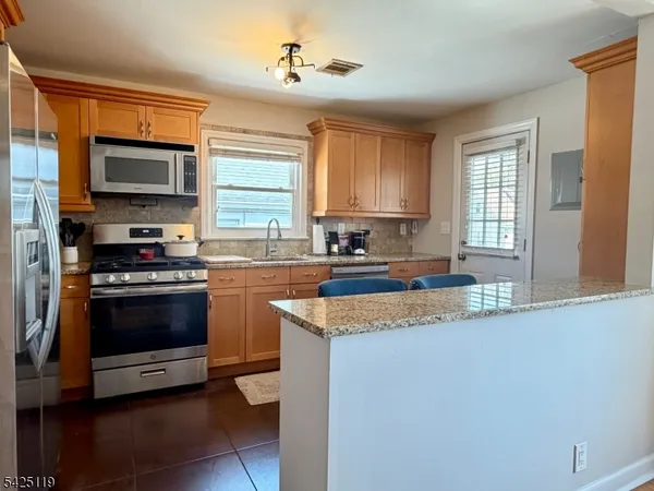 a kitchen with stainless steel appliances granite countertop a stove a sink and a microwave