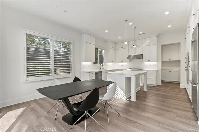 a open dining room with kitchen island a stove a table and chairs