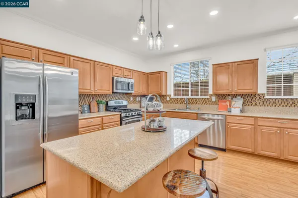 a kitchen with stainless steel appliances granite countertop a refrigerator a sink dishwasher a stove and white cabinets with wooden floor