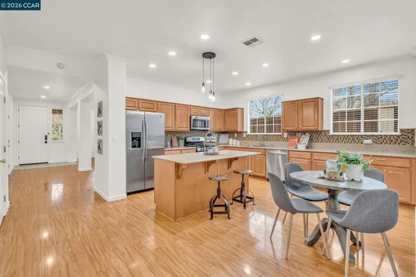 a kitchen with stainless steel appliances granite countertop a sink dishwasher stove refrigerator and cabinets