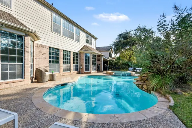 an aerial view of a house with a swimming pool a yard and a large tree