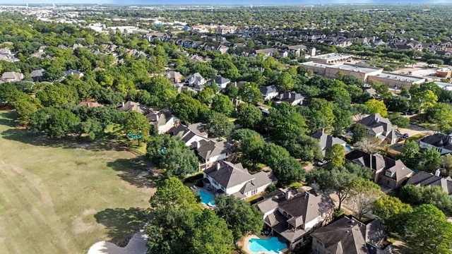 an aerial view of residential houses with outdoor space and trees