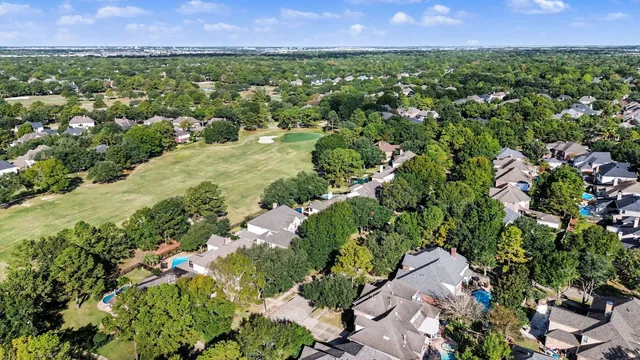 an aerial view of residential houses with outdoor space and trees