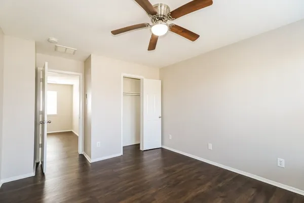 an empty room with wooden floor chandelier fan and closet area