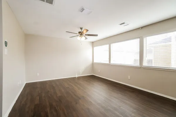an empty room with wooden floor and windows