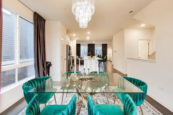 a view of a dining room with furniture a kitchen and chandelier