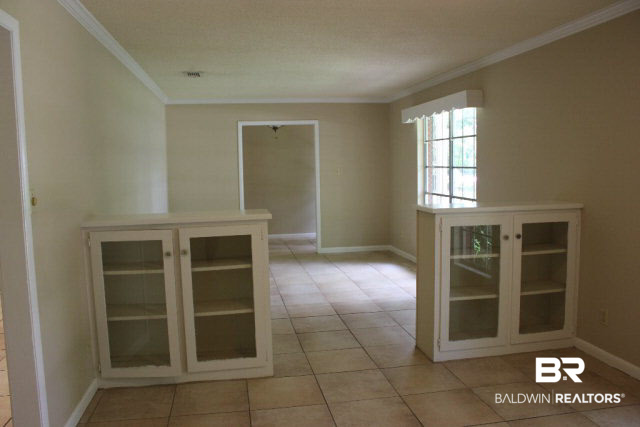 18832 Florida Street Robertsdale, AL 36567 - Photo 6 of 20 Dining room has crown molding, built in cabinets, cornice board over window plus more shelving for display.