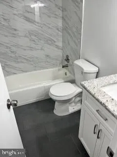 a bathroom with a granite countertop toilet and a bathtub