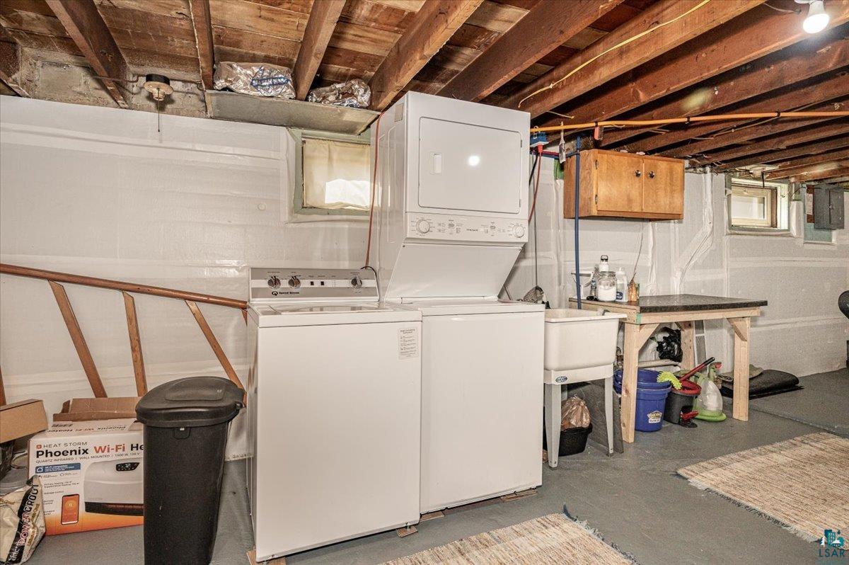 415 14th Street Cloquet, MN 55720 - Photo 13 of 20 Laundry area featuring finished concrete floors, stacked washer / dryer, electric panel, and cabinet space