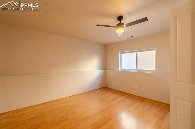 an empty room with a ceiling fan and window