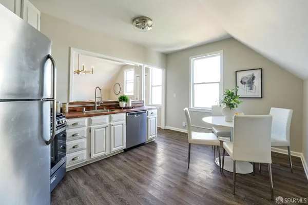 a kitchen with stainless steel appliances granite countertop a refrigerator a sink dishwasher a dining table and chairs with wooden floor