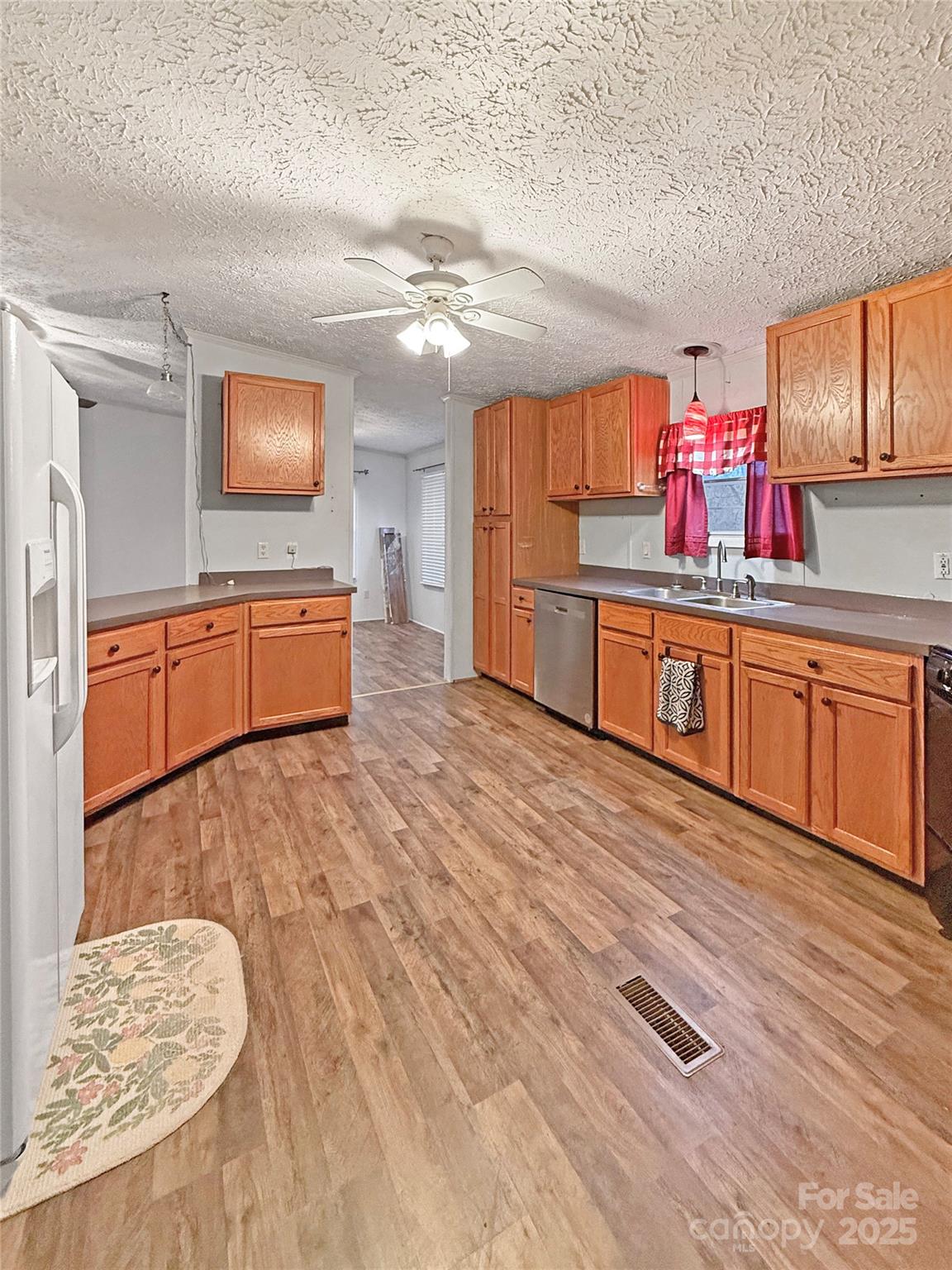 a kitchen with stainless steel appliances granite countertop a sink dishwasher and a stove with wooden floor