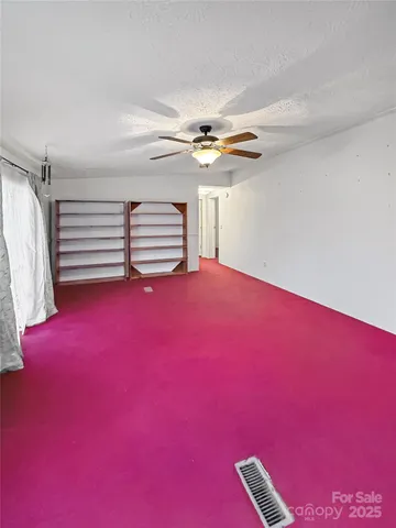 a view of empty room with fireplace and fan