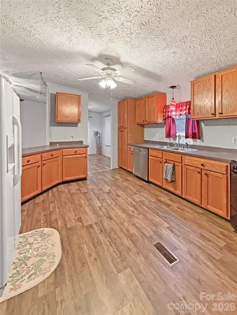a kitchen with stainless steel appliances granite countertop a sink dishwasher and a stove with wooden floor