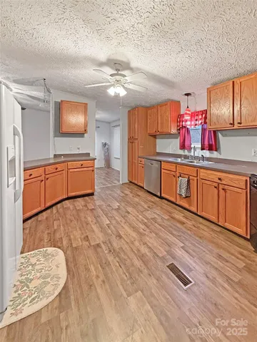 a kitchen with stainless steel appliances granite countertop a sink dishwasher and a stove with wooden floor