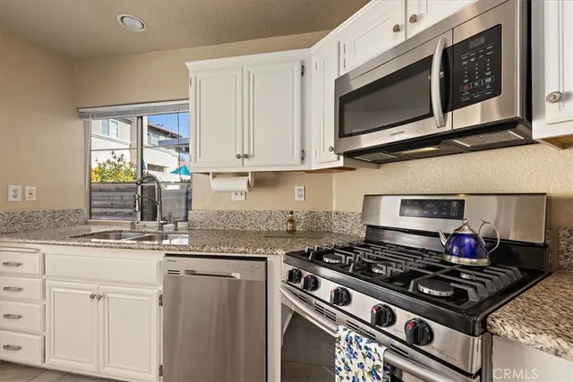 a kitchen with stainless steel appliances granite countertop white cabinets and a stove top oven