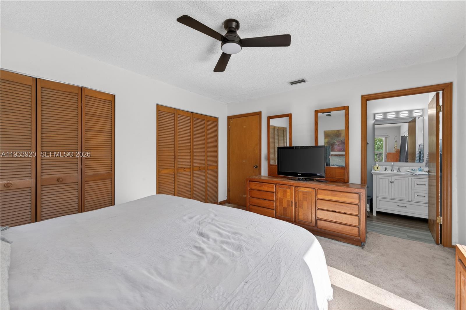 13228 158th Street North Jupiter, FL 33478 - Photo 12 of 21 a bedroom with a bed a dresser and a flat screen tv
