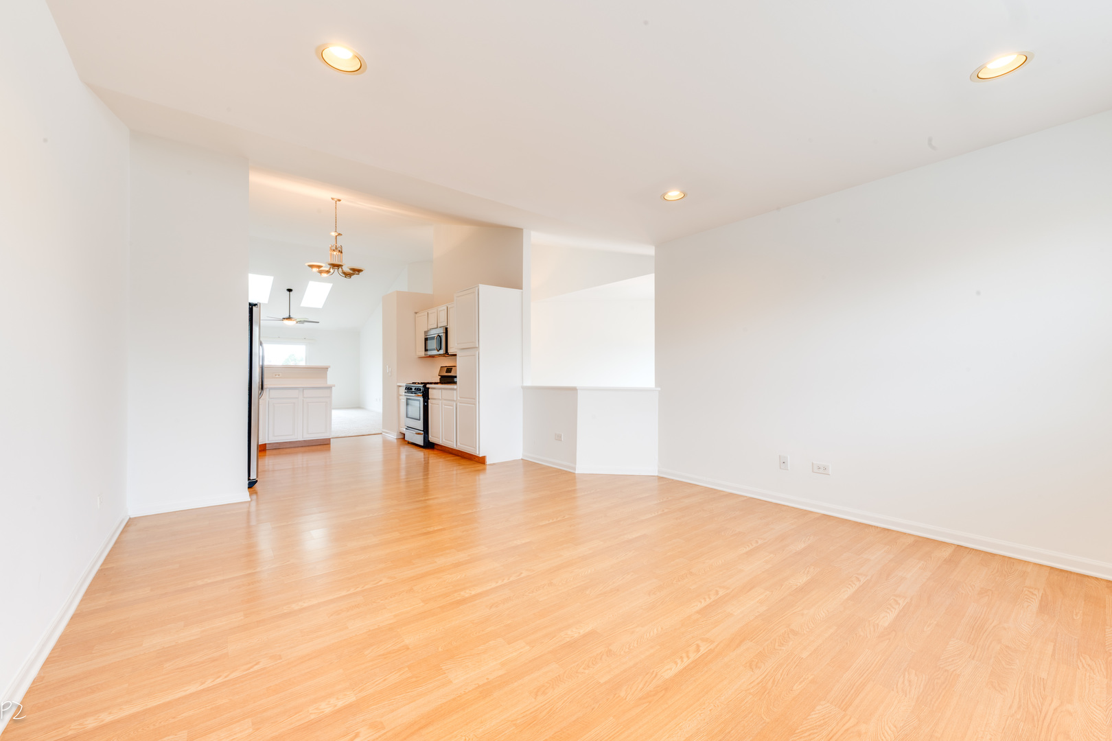 24181 Pear Tree Circle Plainfield, IL 60585 - Photo 9 of 25 a view of an empty room with wooden floor and a kitchen