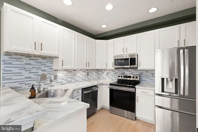 a kitchen with granite countertop a sink stainless steel appliances and white cabinets