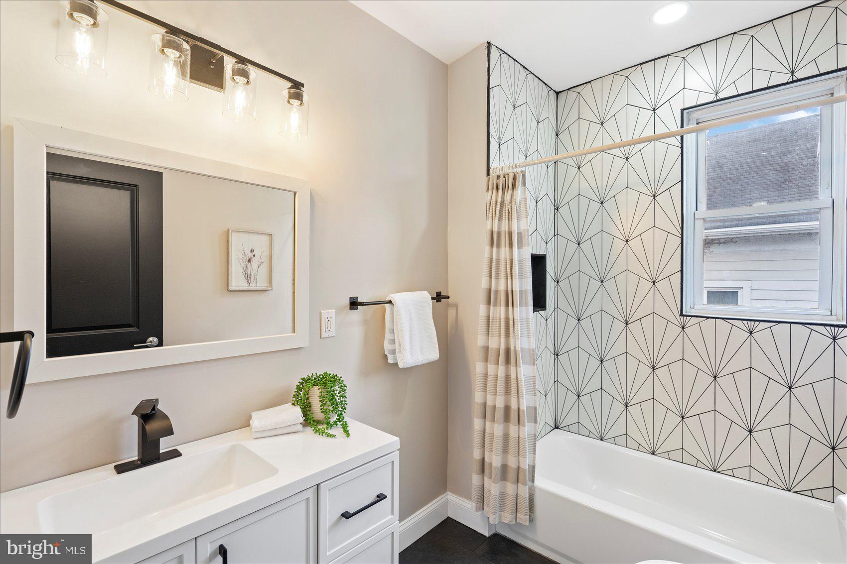 3925 Norfolk Avenue Baltimore, MD 21216 - Photo 30 of 49 a bathroom with a sink a mirror a bathtub and shower