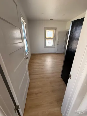 a view of a hallway to a livingroom with wooden floor and stairs